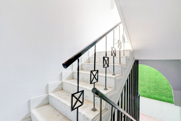A staircase with white marble steps and black metal railings.
