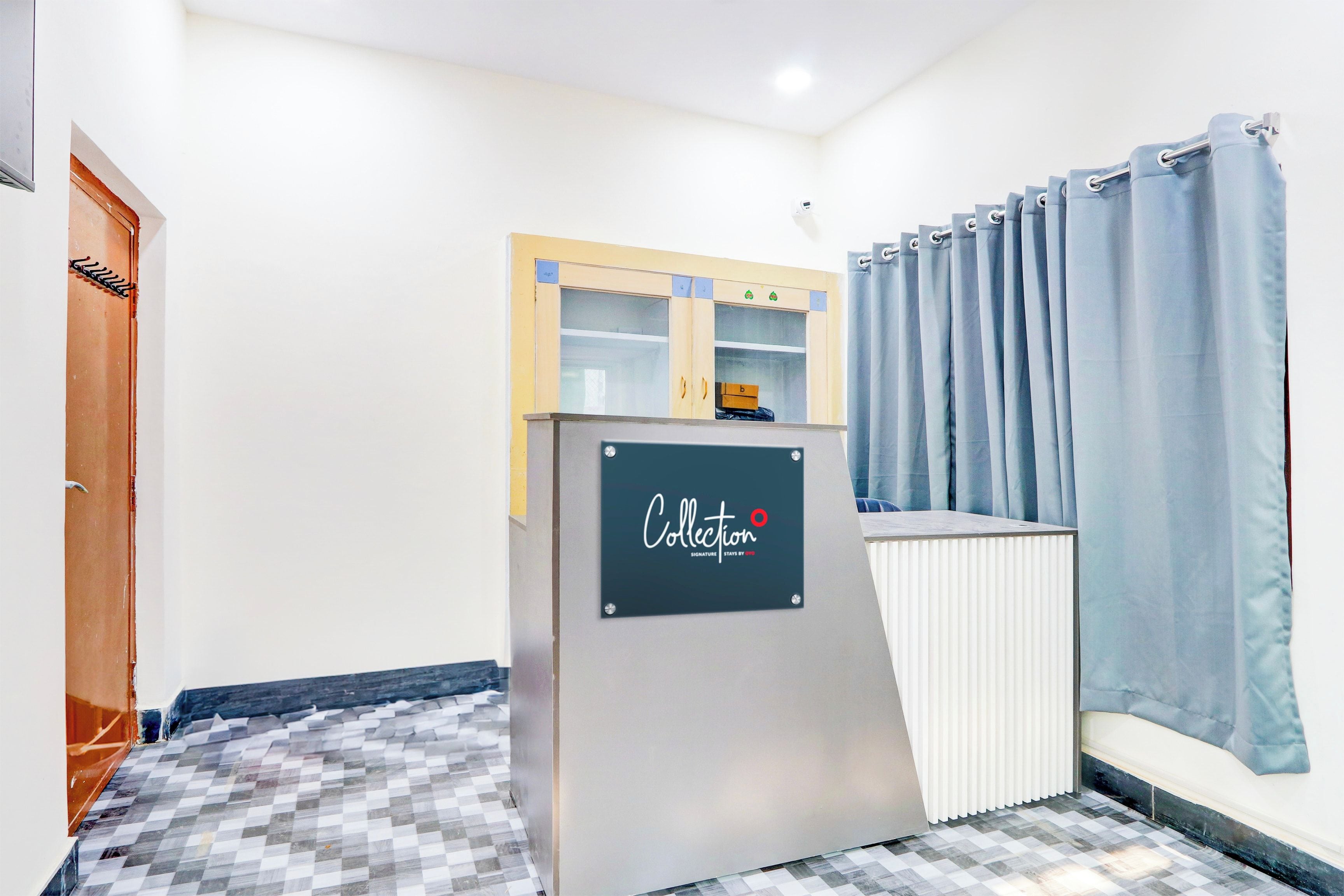 A room with a checkered floor, a desk with a sign, a door, and a curtain.