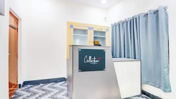 A room with a checkered floor, a desk with a sign, a door, and a curtain.
