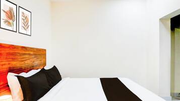 Una habitación de hotel con una cama, almohadas, cabecero y dos cuadros enmarcados.