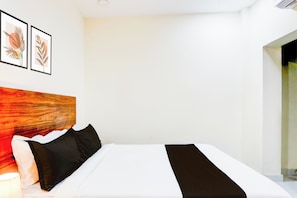 Habitació d'hotel amb un llit, almoines, un capçal i dues obres d'art emmarcades a la paret.