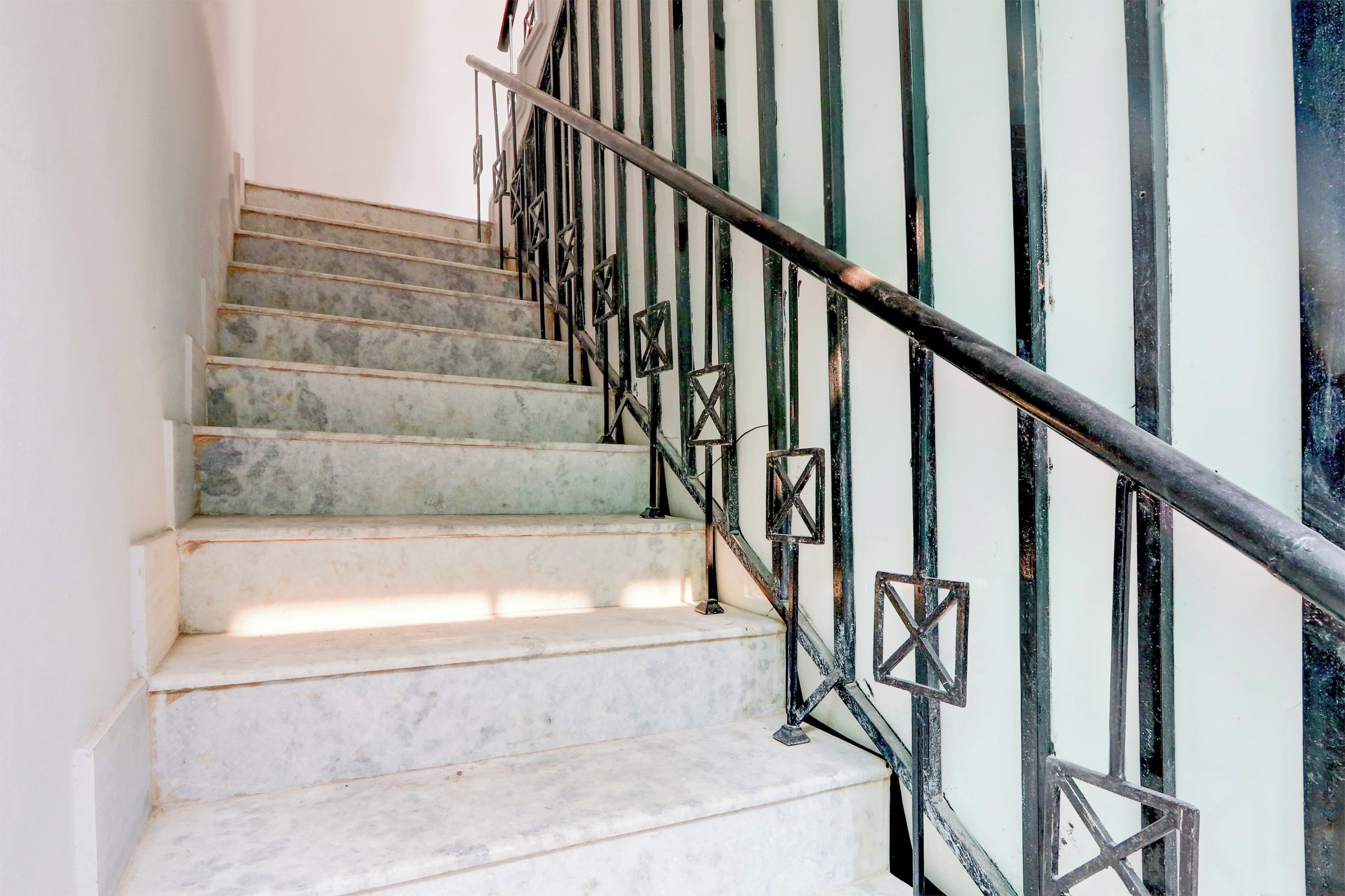 Una escalera con escalones de mármol y barandillas de metal negro.