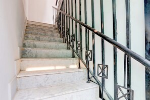 Una escalera con escalones de mármol y barandillas de metal negro.