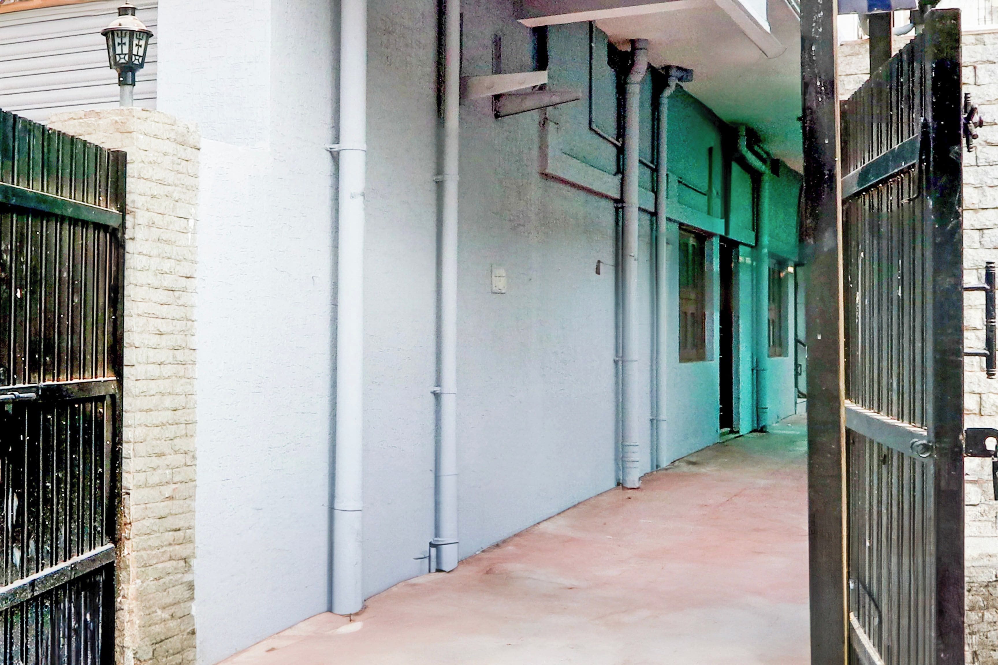 Un pasillo con piso de concreto, barandas de metal y una entrada con reja.
