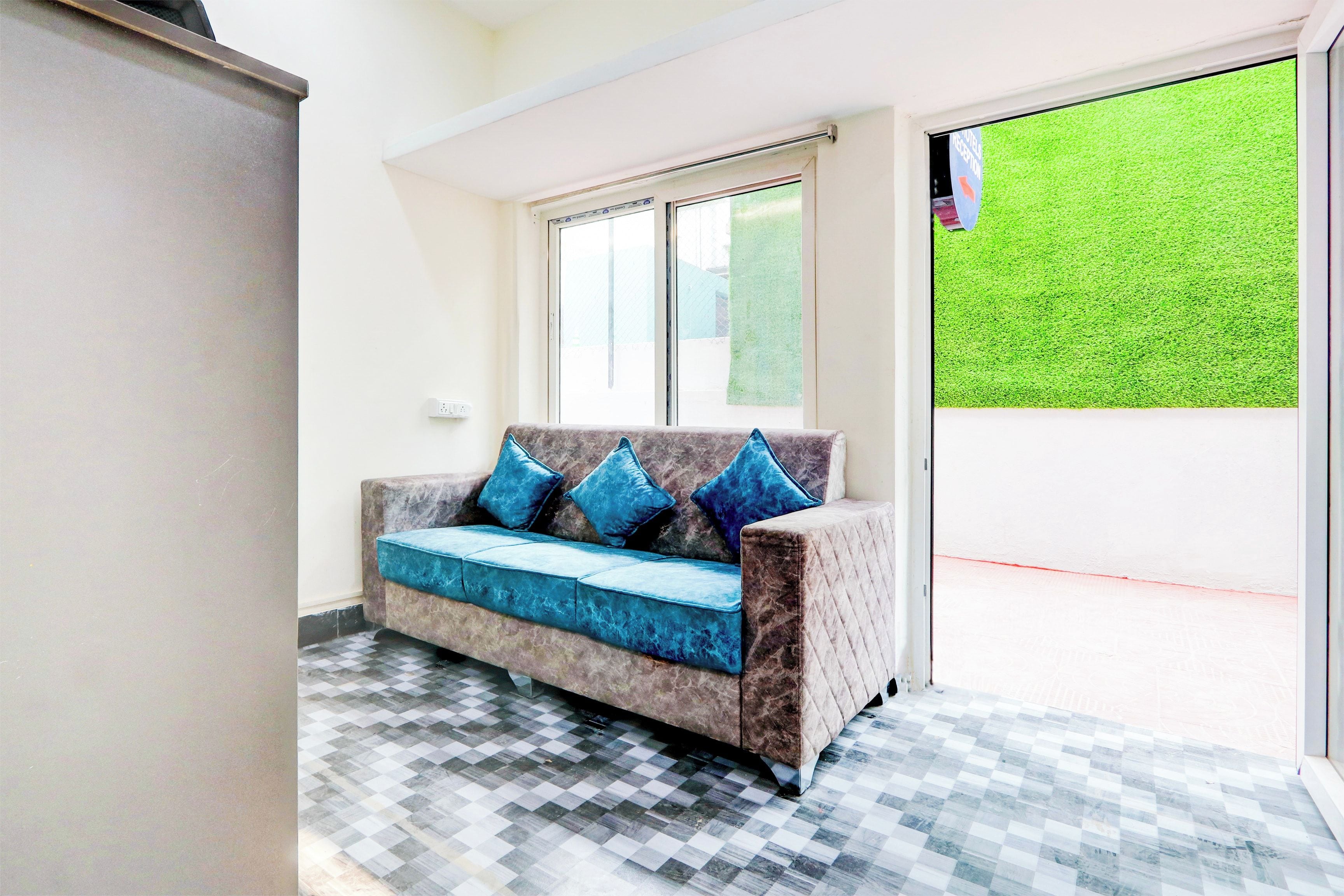 Una habitación con sofá, piso a cuadros, ventana y vista a un césped verde.