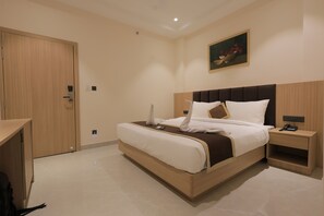 Una habitació d'hotel amb un llit, una taula de nit i un quadre a la paret.