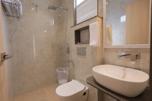 Un bany amb vàter, rentapel, dutxa i un penjador de tovalloles.