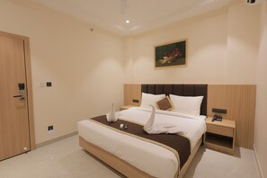 Una camera d'albergo con un letto grande, un comodino, un quadro appeso al muro e una porta.