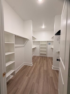 A walk-in closet with open shelving, a door with a black handle, and a light fixture on the ceiling. - Charming 3-bedroom townhome 11 min from Downtown Houston (Houston)
