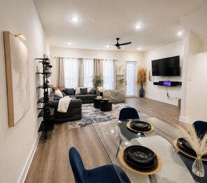 A modern living room with a sofa, coffee table, and dining area. - Charming 3-bedroom townhome 11 min from Downtown Houston (Houston)