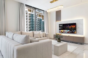 A modern living room with a large flat-screen TV, a sofa, and a coffee table. - Premium 5BR Sobha Crest Grande (Dubai)