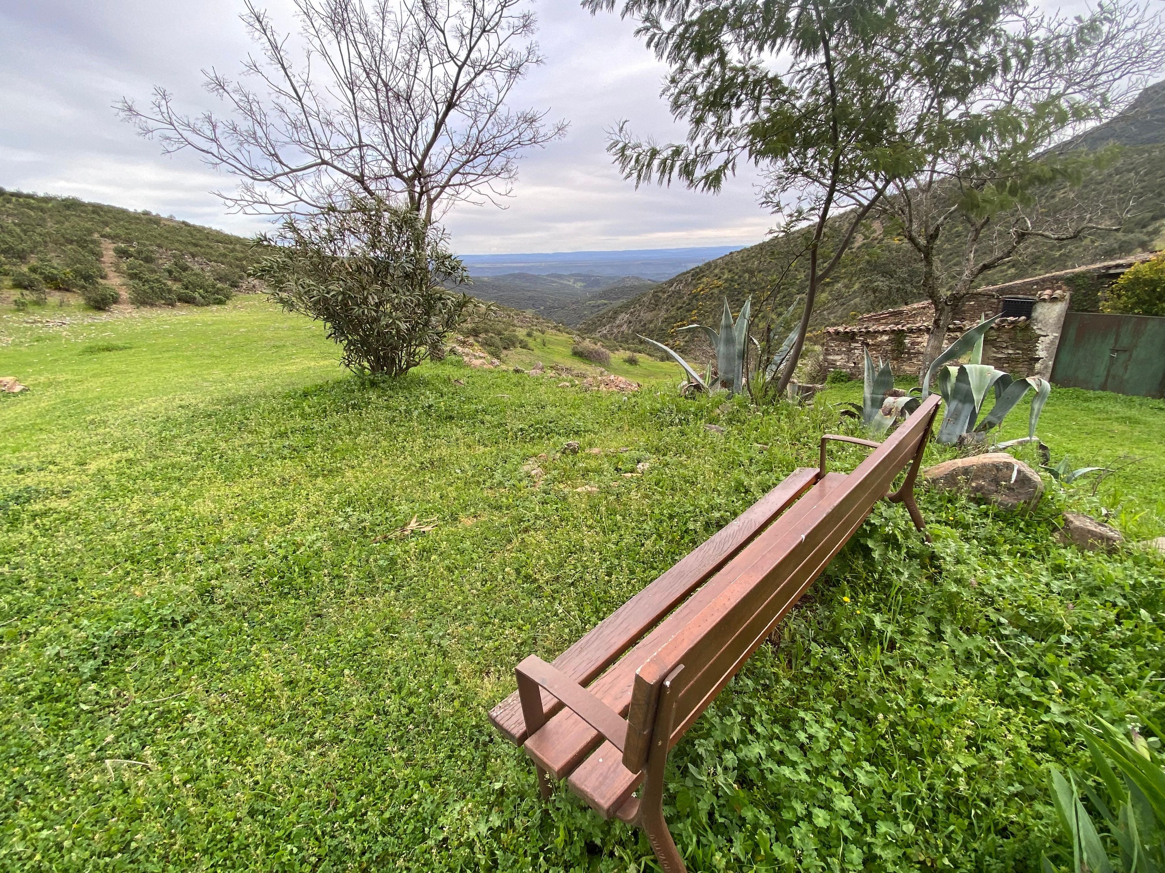 Un banco en un área verde con vistas a un valle y colinas.