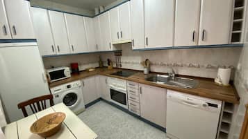 A compact kitchen with white cabinets, a microwave, a coffee maker, a sink, and a dishwasher.