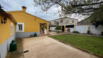 Una zona residencial con un edificio amarillo, un camino de entrada pavimentado y un pequeño jardín.
