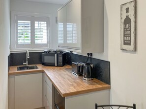 A compact kitchen with a microwave, toaster, and sink. - 1 bedroom accommodation in Inverness (Inverness)
