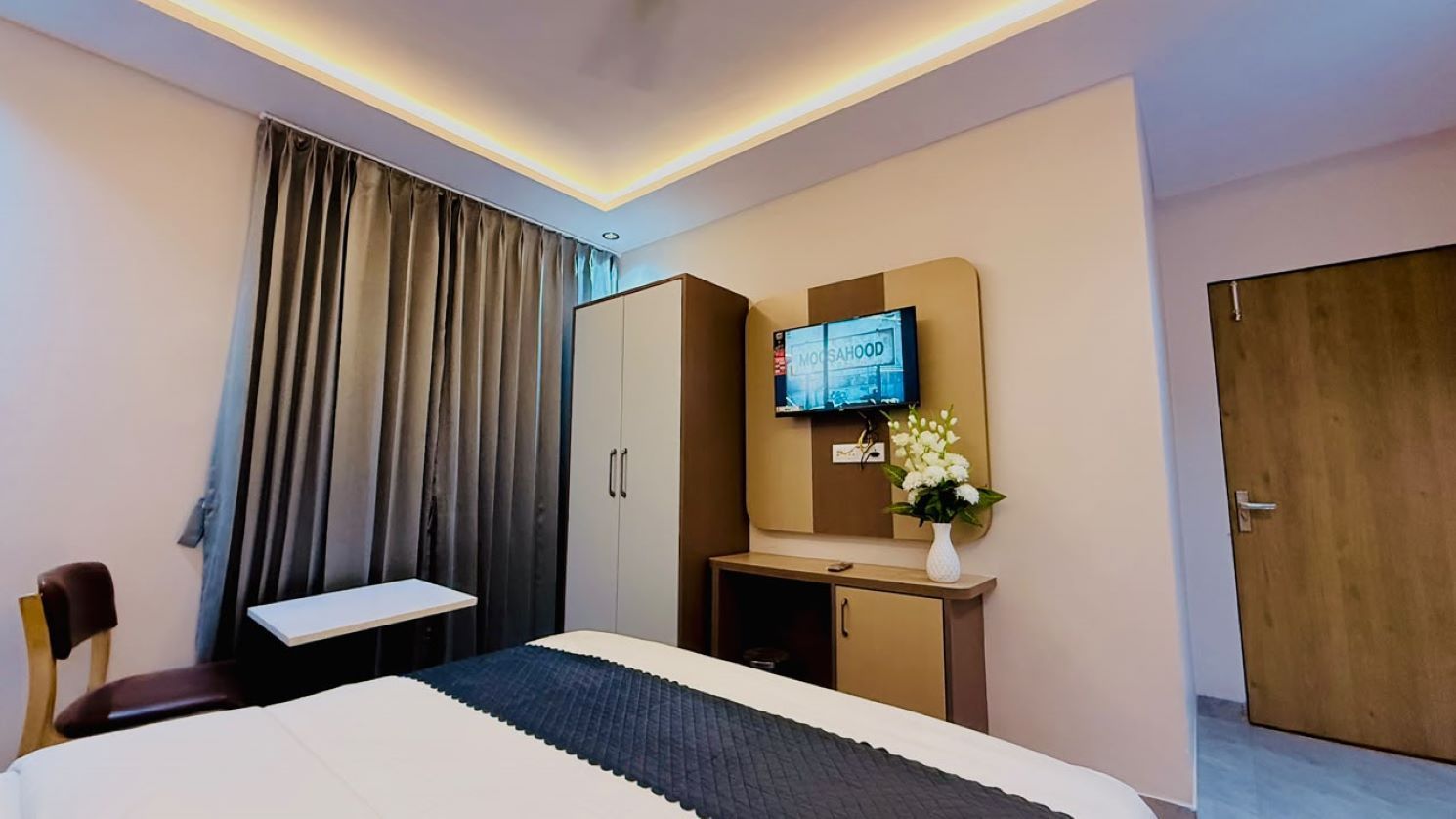 Una habitación de hotel con cama, escritorio, televisión y armario.