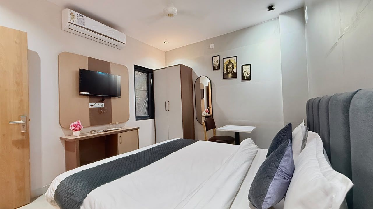 A hotel room with a bed, a desk, a wardrobe, a television, and wall-mounted artwork.