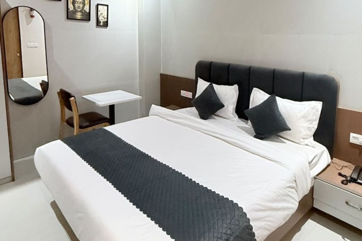 Una camera d'albergo con un letto, una scrivania, una sedia, uno specchio e una ventola a soffitto.