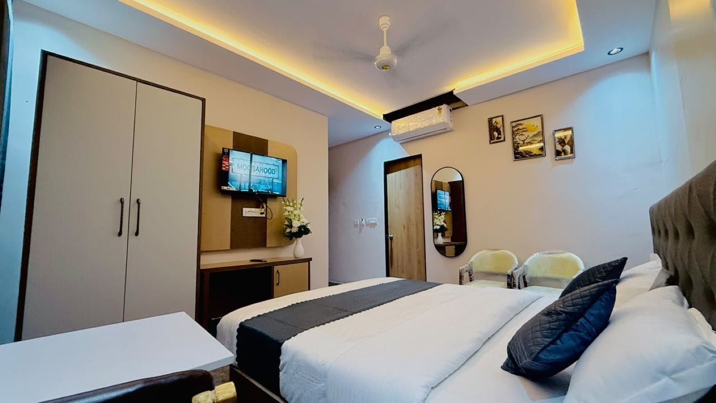 A hotel room with a bed, a desk, a TV, a mirror, and a wardrobe.