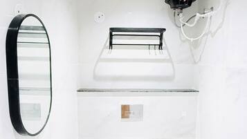A modern bathroom with a white sink, a toilet, a mirror, and a ceiling-mounted toilet paper holder.