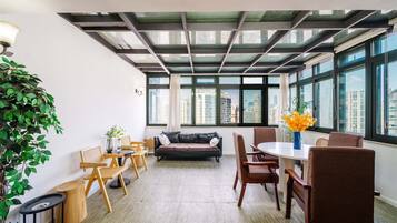 Decoração moderna com pé direito alto, grandes janelas, uma mesa redonda e disposição de assentos.