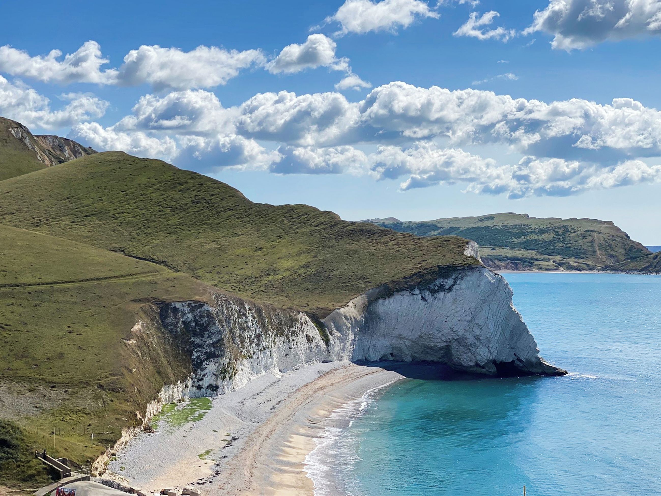 A coastal landscape with a prominent white cliff and a beach.