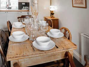 A wooden dining table set with white bowls, glasses, and cutlery, surrounded by wooden chairs. - 3 bedroom accommodation in Dorchester (Dorchester)