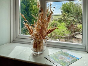 A clear view of a window with a vase of dried flowers on a windowsill, a small table, and a printed brochure. - 3 bedroom accommodation in Dorchester (Dorchester)