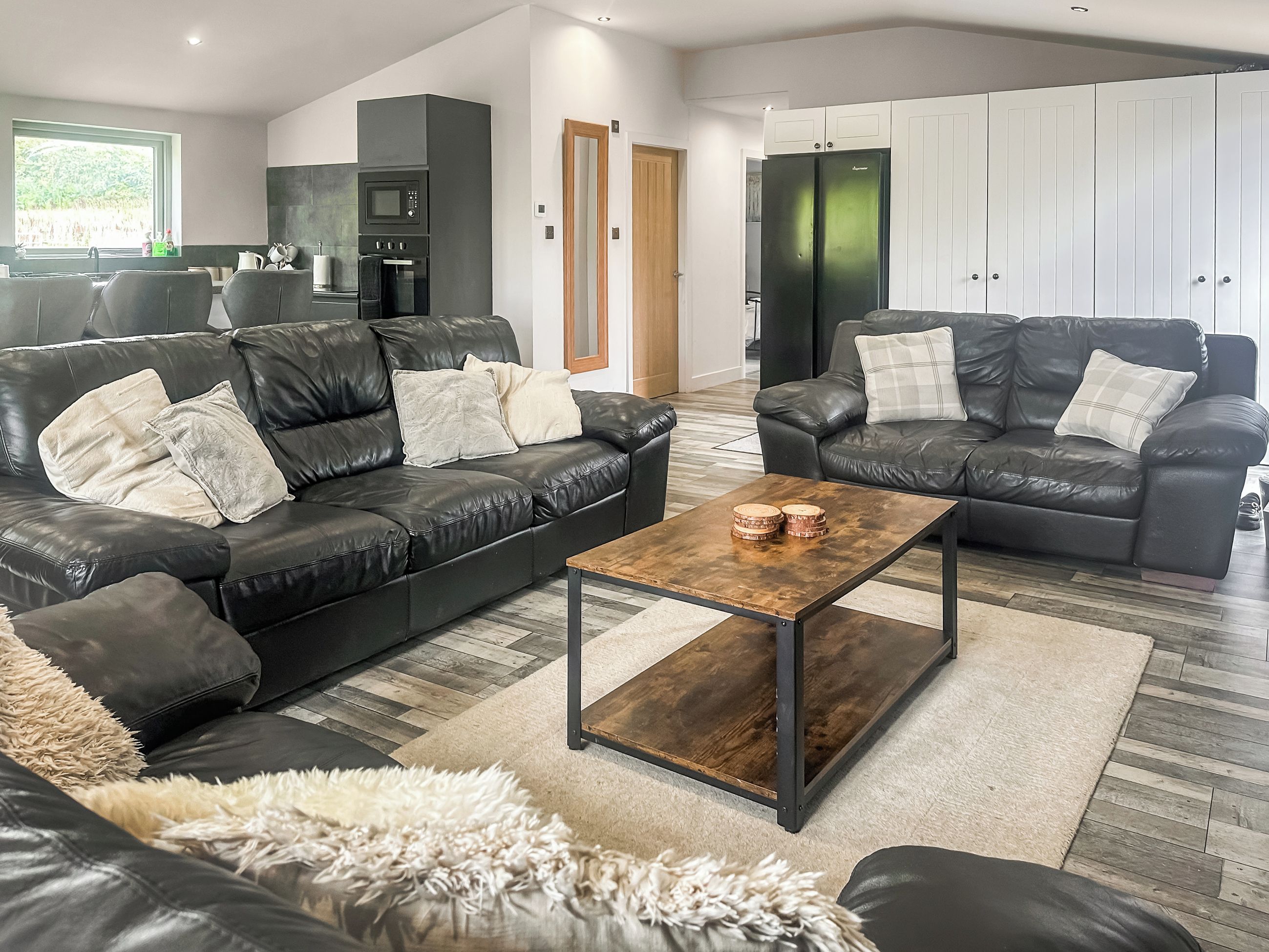 A modern living room with two leather sofas, a wooden coffee table, and a fluffy rug.