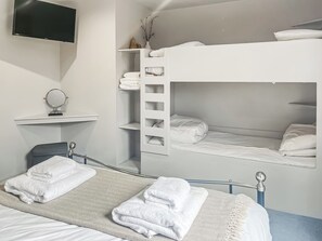 Habitación con literas, televisor montado en la pared, un espejo y un estante con artículos de aseo.