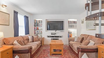 Ett vardagsrum med två soffor, ett soffbord, en tv och en bokhylla.