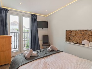 Une chambre d’hôtel avec un lit, une télévision, un décor mural en pierre et une vue sur l’extérieur.