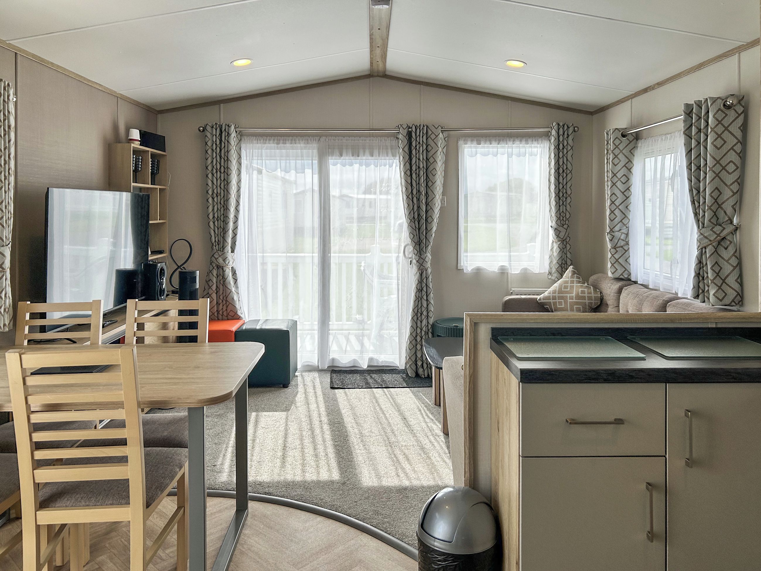 Een knus woongedeelte met een eettafel, stoelen, een bank, een televisie en een kitchenette.