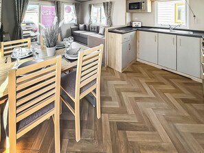 A compact kitchen with a dining area, herringbone wood flooring, and a view of the street. - Northfield Lodge 2 - UK52396 (Skipsea Sands)