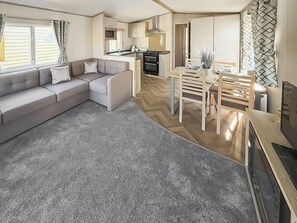 A compact living space with a sofa, dining table, chairs, a kitchenette, and a TV. - Northfield Lodge 2 - UK52396 (Skipsea Sands)