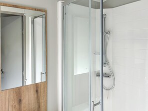 A bathroom with a glass shower enclosure, a wooden vanity, and a white tiled wall. - Northfield Lodge 2 - UK52396 (Skipsea Sands)