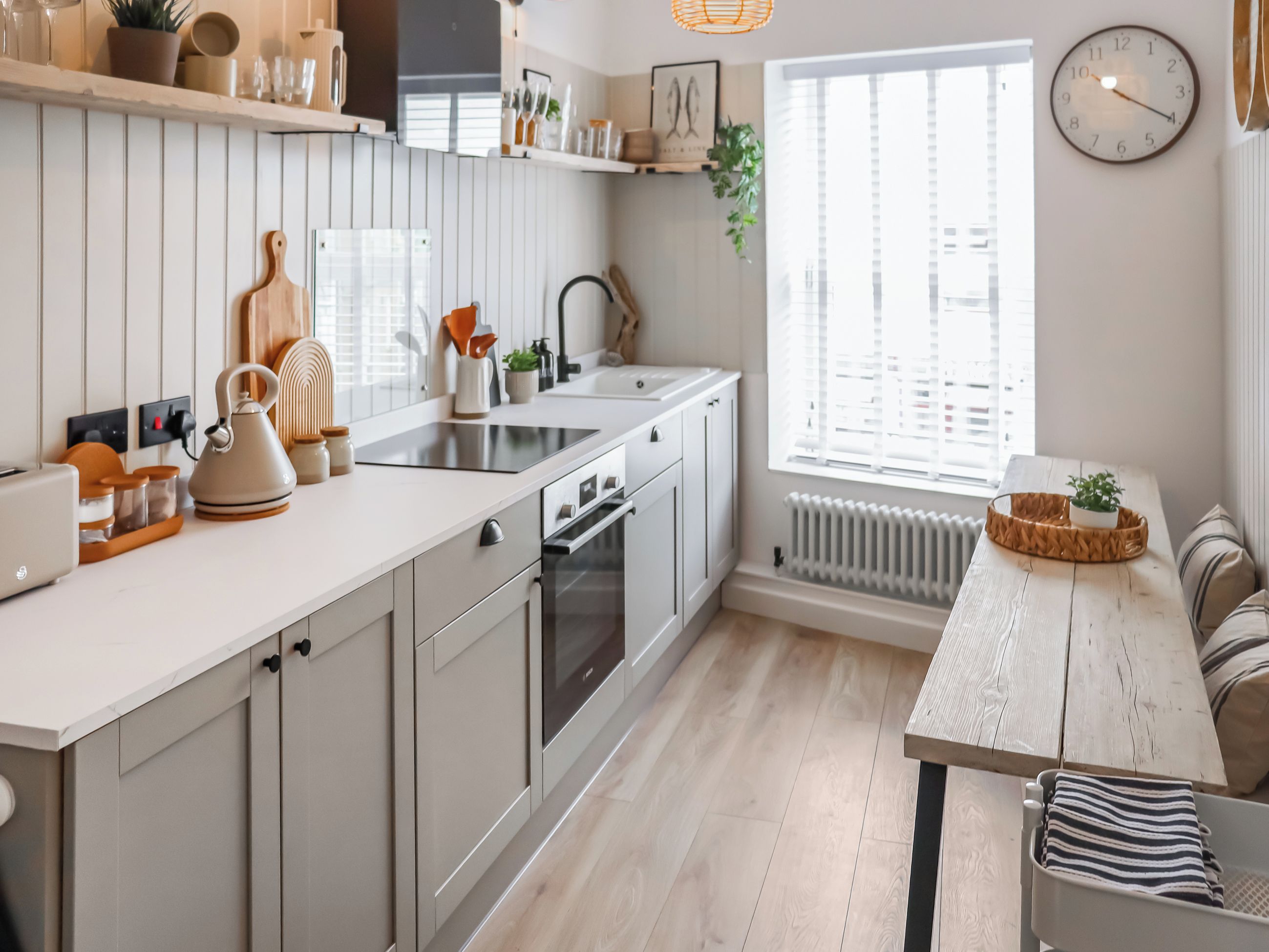 Una cucina moderna con forno integrato, lavello e zona pranzo con panche e cuscini a righe.
