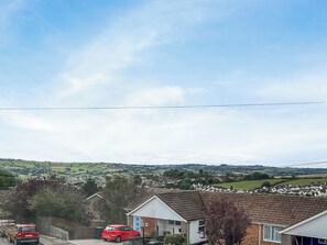 A residential area with houses, a red car parked in front, and a clear sky. - 2 bedroom accommodation in Teignmouth (Teignmouth)