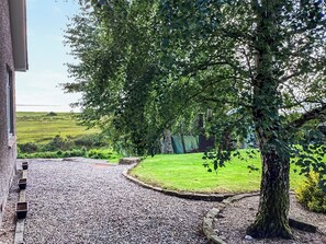 A gravel pathway leading to a grassy area with a tree and a building on the left. - 3 bedroom accommodation in Dornoch (Dornoch)