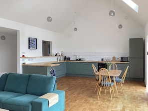 A modern kitchen with a dining area, a sofa, and a ceiling light fixture. - Welcome to Otter House a beautiful new build bungalow, located in Sand, Laide. (Laide)
