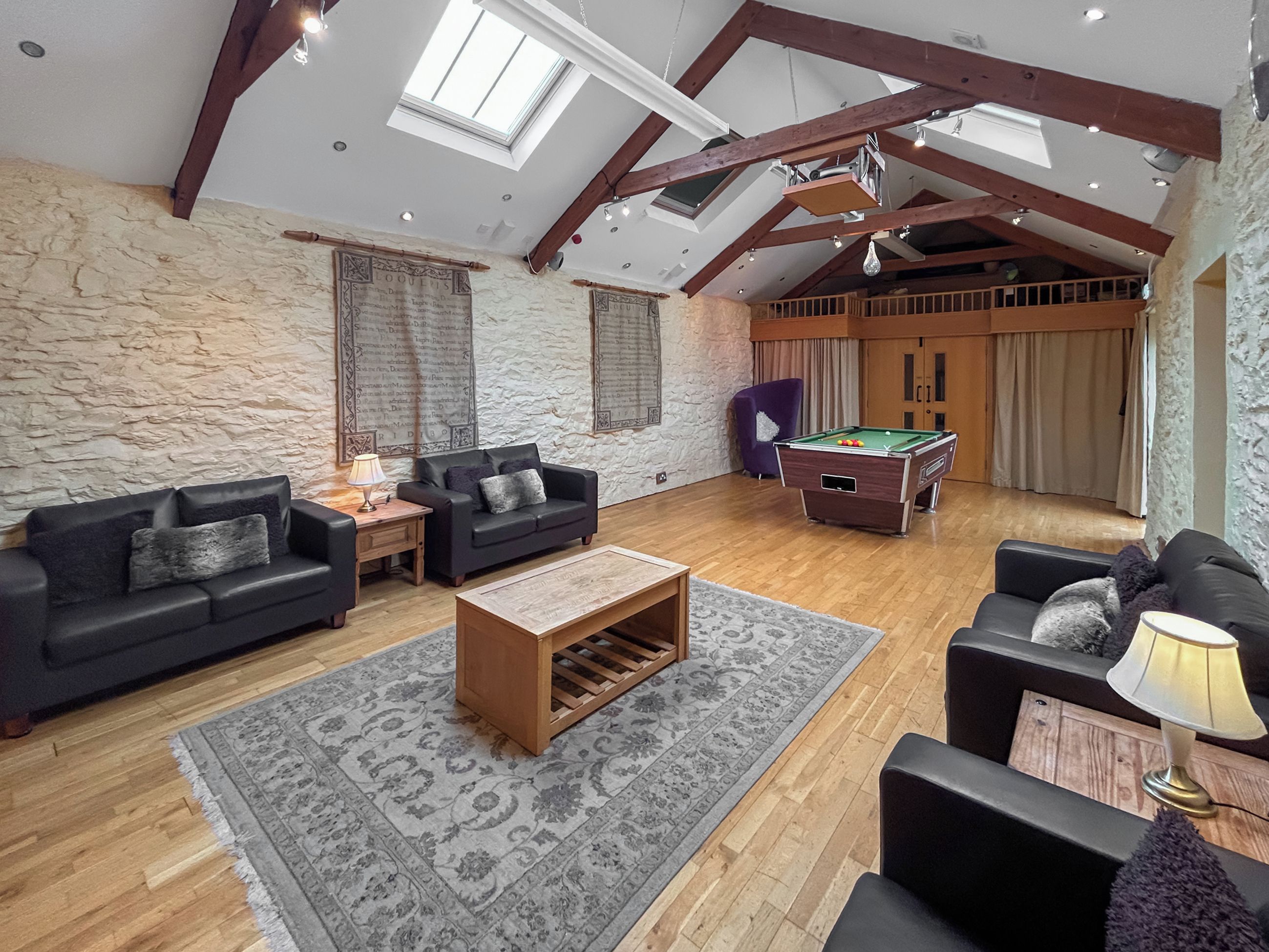 A spacious living room with a pool table, two sofas, a coffee table, and a billiards table.