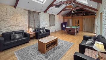 A spacious living room with a pool table, two sofas, a coffee table, and a billiards table.