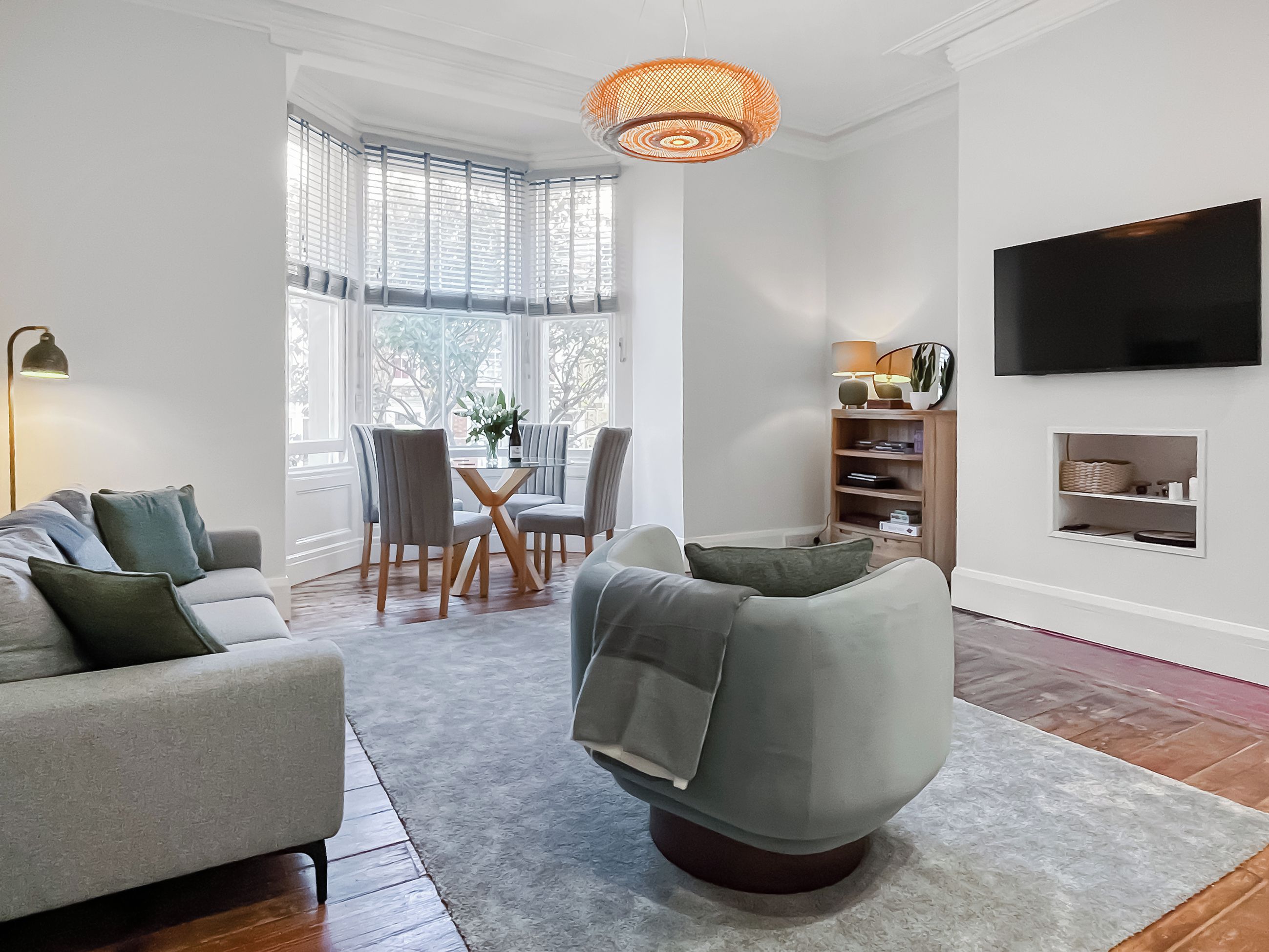 Una sala de estar moderna con un sofá gris, una mesa de centro redonda y un comedor con mesa y sillas.