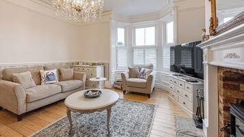A living room with a sofa, armchair, coffee table, fireplace, and a television.