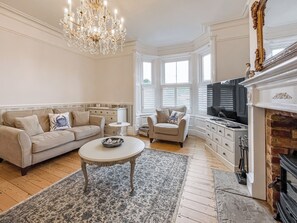 A living room with a sofa, armchair, coffee table, fireplace, and a television. - 5 bedroom accommodation in Whitby (Whitby)