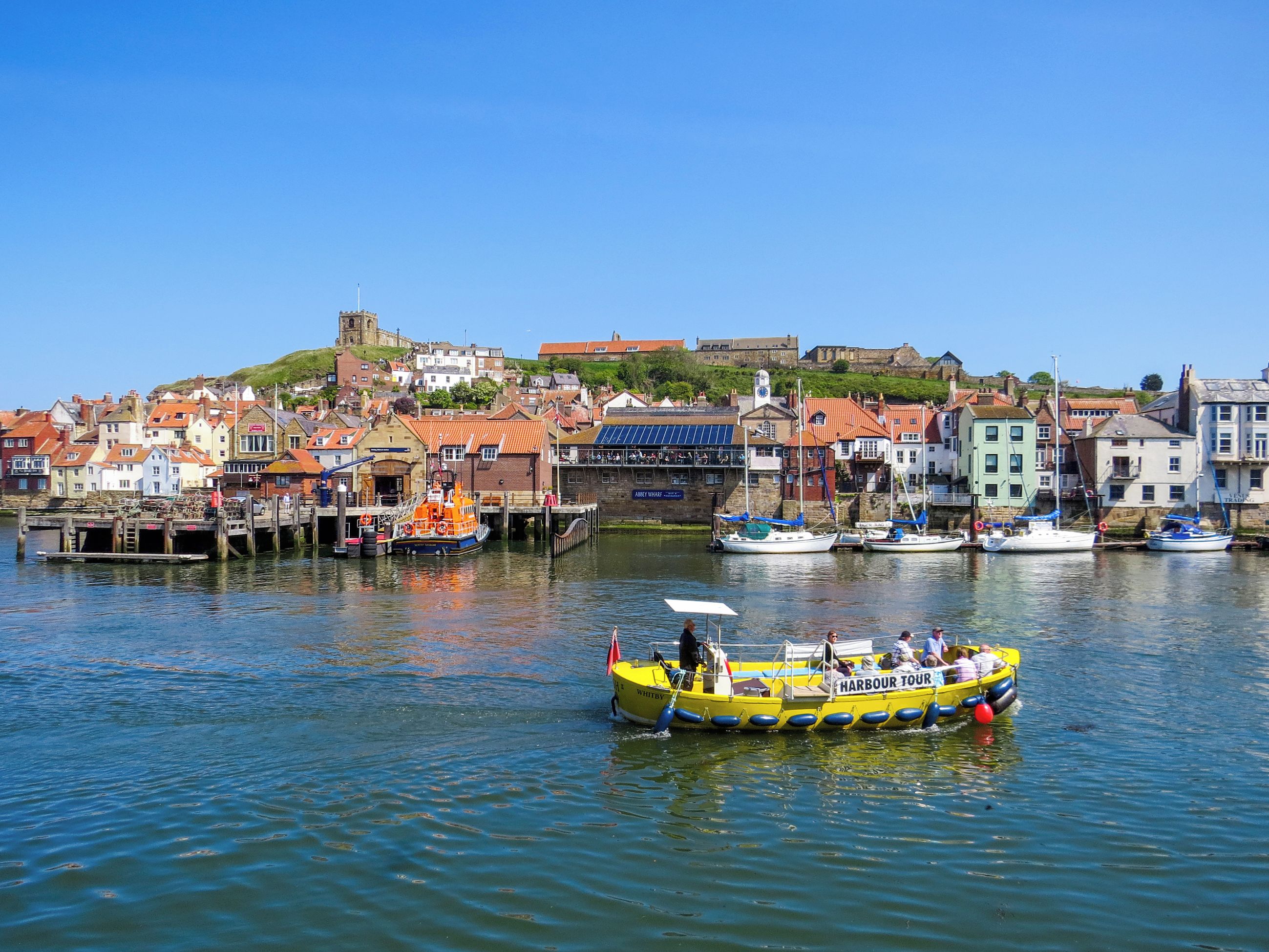 Un porto con barche, un molo e una città sullo sfondo.
