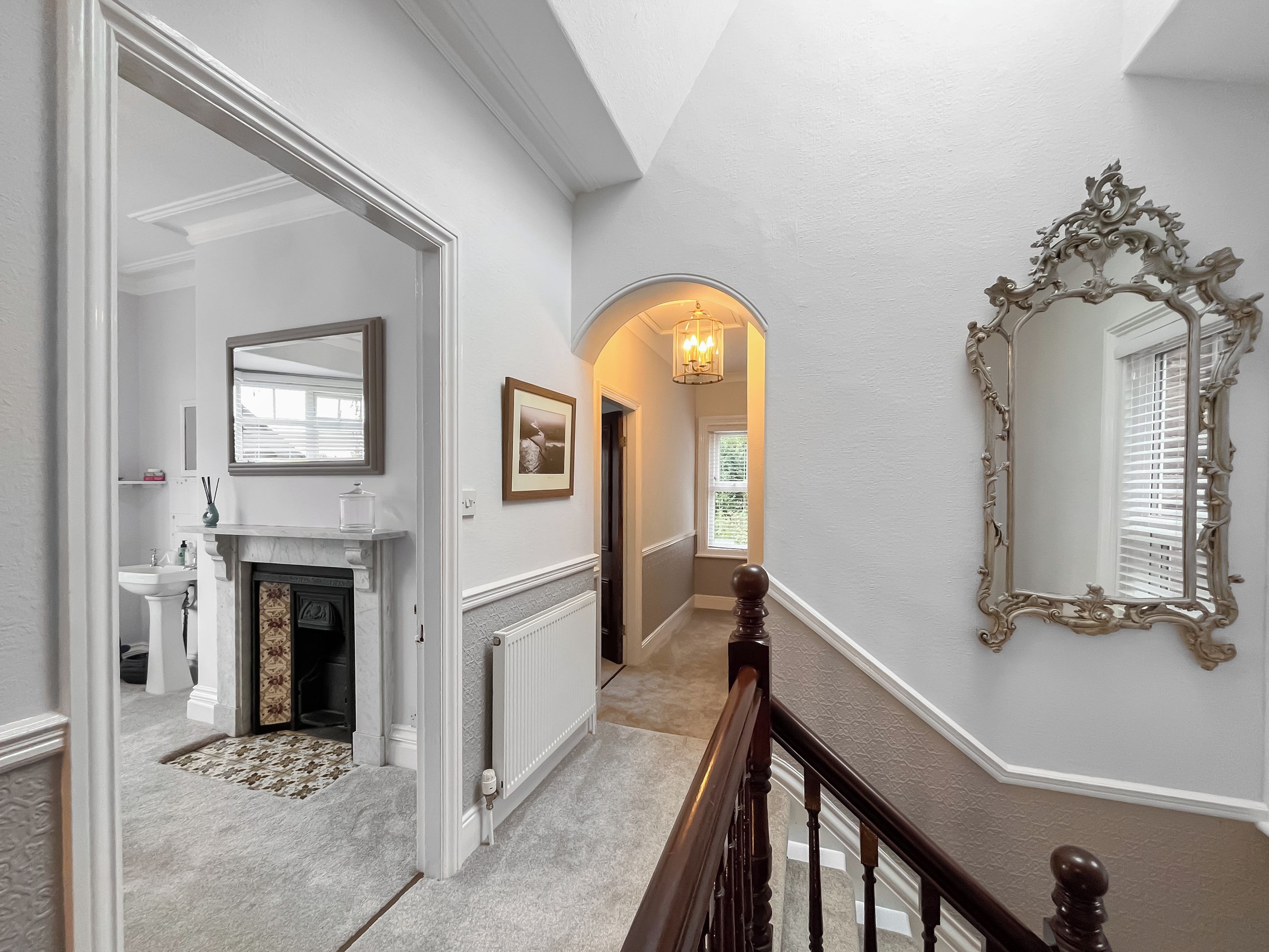 A hallway with a fireplace, a mirror, and a radiator.