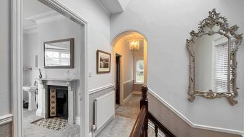 A hallway with a fireplace, a mirror, and a radiator.