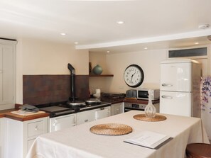 A kitchen with a stove, microwave, and refrigerator. There is a clock on the wall and a table with placemats. - 3 bedroom accommodation in Rye (Rye)