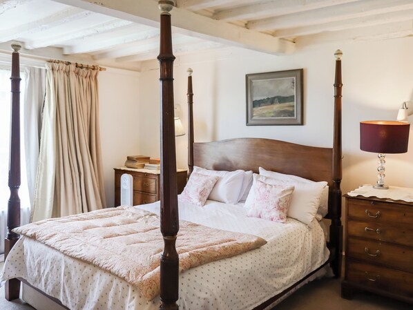 A four-poster bed with a wooden headboard, a bedside table with a lamp, and a nightstand with a lamp. - 3 bedroom accommodation in Rye (Rye)